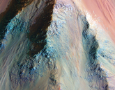 Three multicolored ridges, converging near the top of the image. Giant Valles Marineris is up to 10 kilometers deep; this is just a small part near the bottom of a giant slope connecting the upper plains to the canyon floor. The varied colors indicate a mix of altered and unaltered rocks in this deep exposure of ancient Mars.